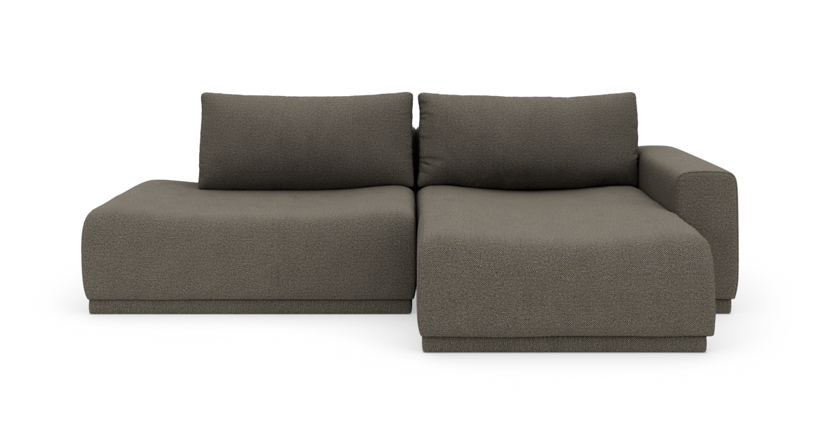 Modulsofa i mørkegrå tekstil med venstre chaiselong og højre armlæn, fritstående på hvid baggrund.