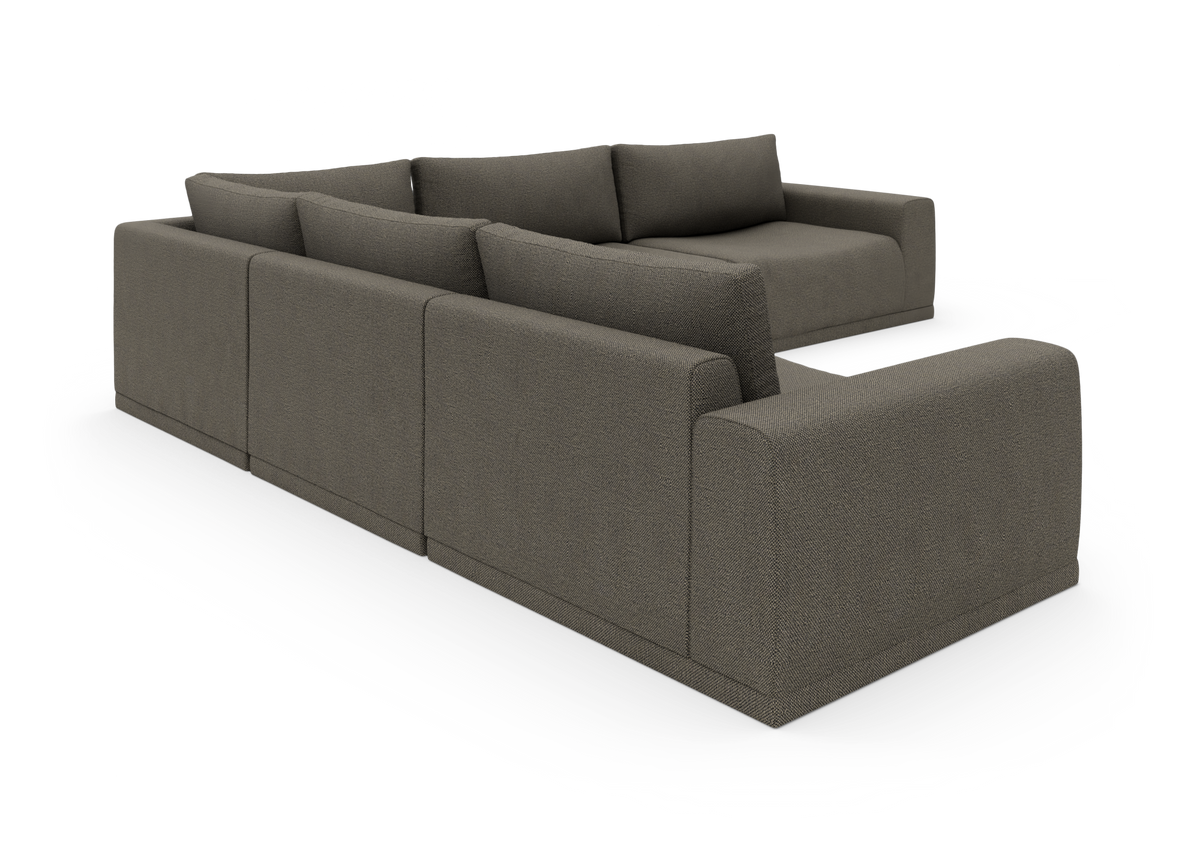 Modulær hjørnesofa i mørkegråt stof, vist i studie fra skråt bagfra.