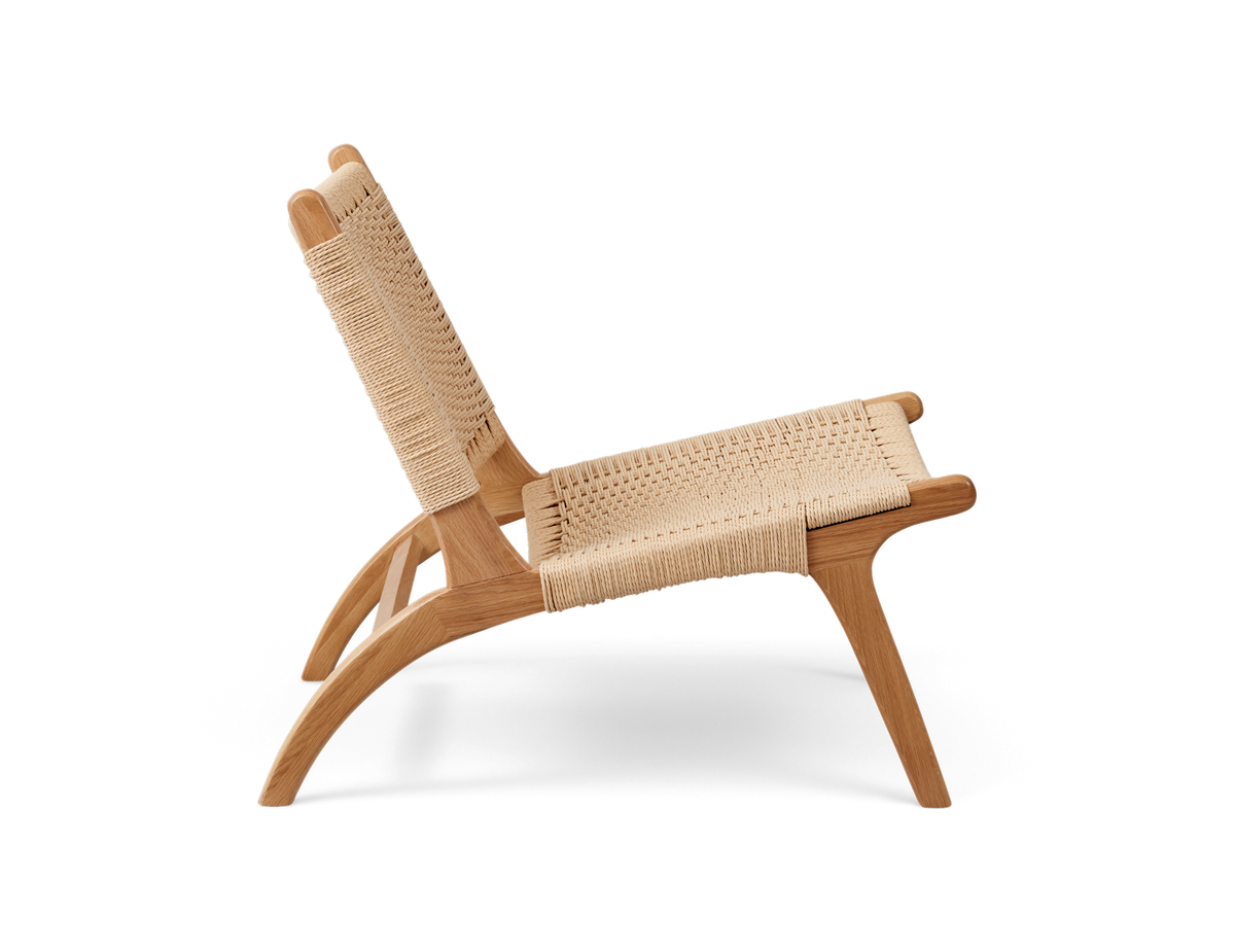 Lav loungestol i lyst egetræ med flettet sæde og ryg i naturfibre, frilagt sidevisning.