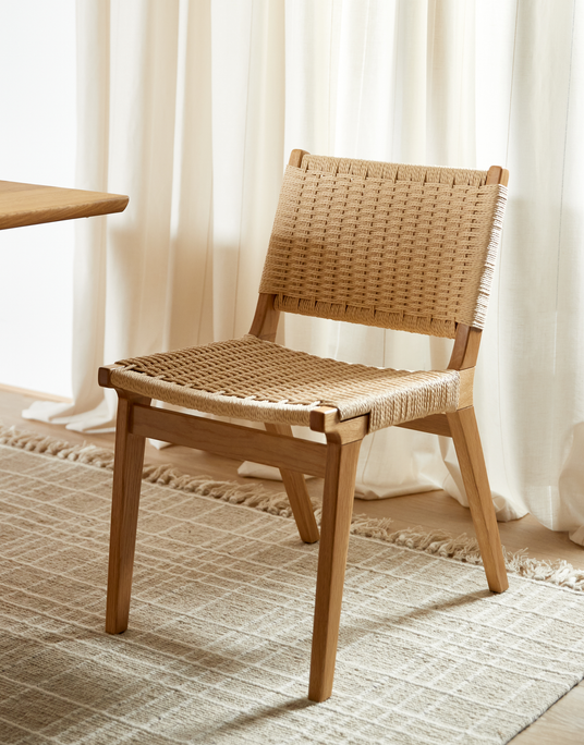 Stol i lys eg med flettet sæde og ryg, placeret på beige tæppe ved lyse gardiner i dagslys.
