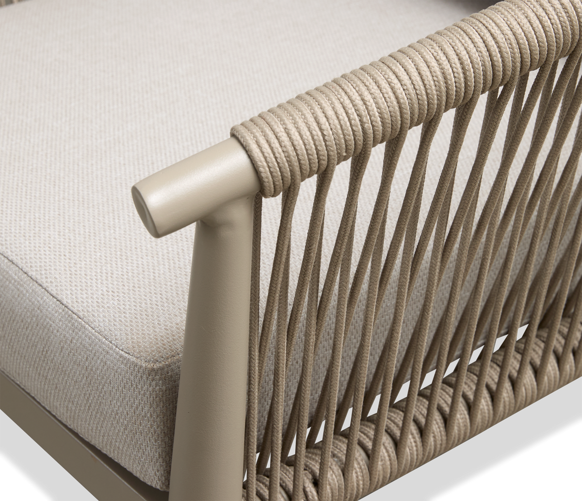 Detalje af beige stol med rebomviklet armlæn og flettet side, med lys stofhynde.