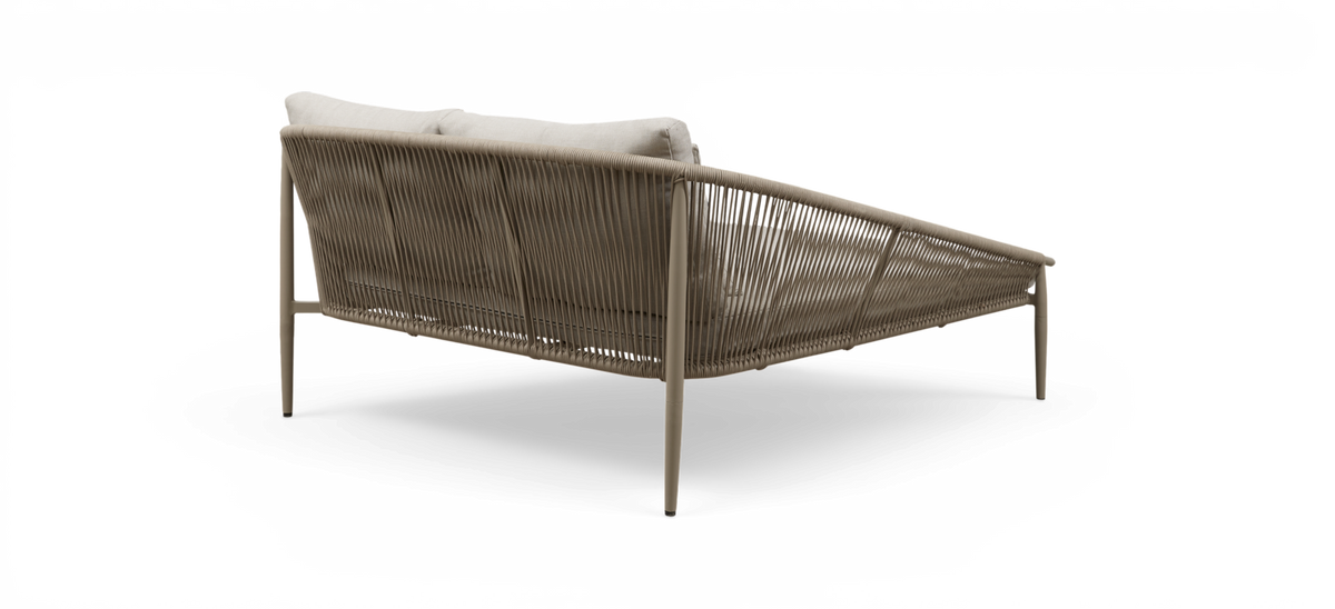 Beige loungesofa med flettet rebryg og lyse puder, set skråt bagfra i studiemiljø.