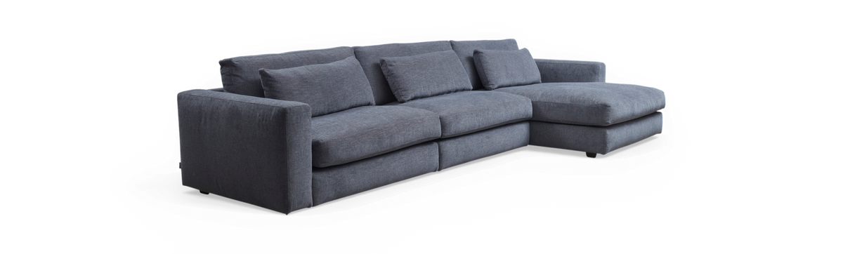 Blågrå hjørnesofa med chaiselong til højre på sort baggrund.