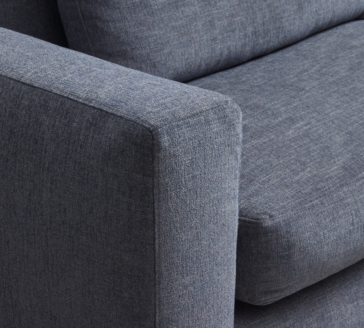 Nærbillede af blå stofbetrukket sofa-armlæn med sæde- og ryghynde.