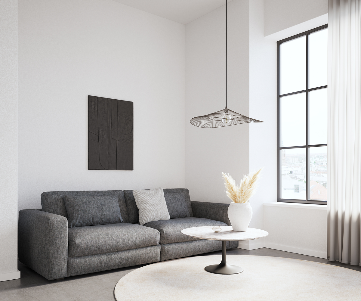 Lyst skandinavisk stuehjørne med grå sofa, rundt sofabord med marmorlook, hvid vase med pampasgræs, stort sort sprossevindue og let trådpende l.