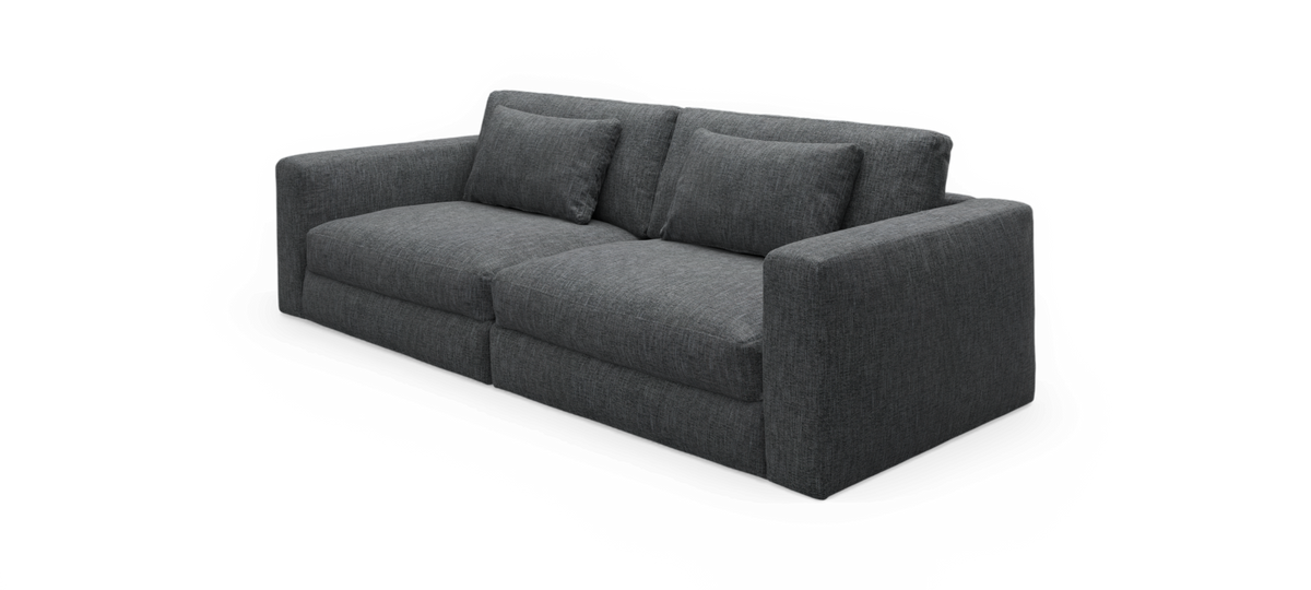 Mørkegrå stofsofa med brede armlæn og to sædehynder, frilagt på sort baggrund.