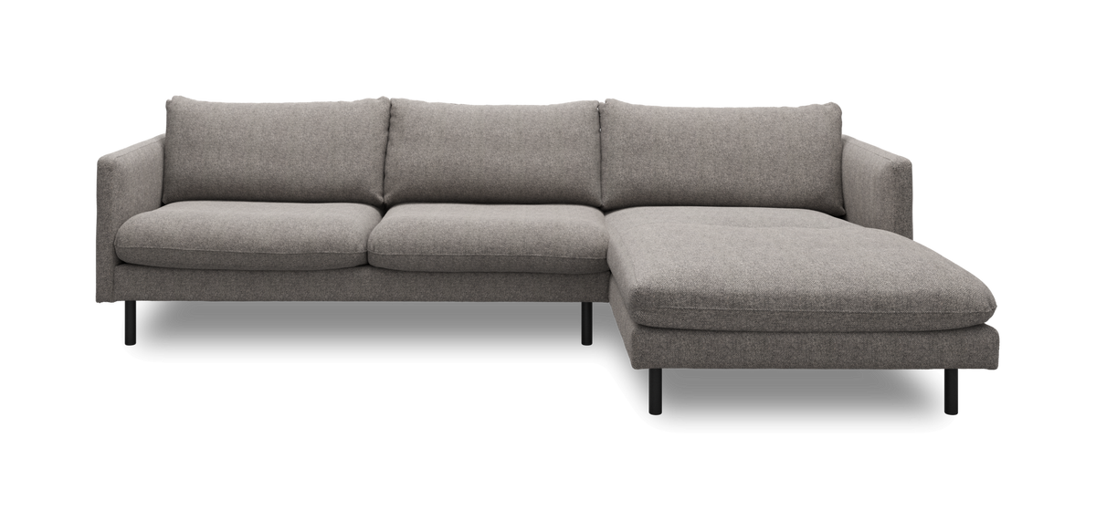 Grå hjørnesofa med chaiselong til højre på slanke sorte ben, frilagt.