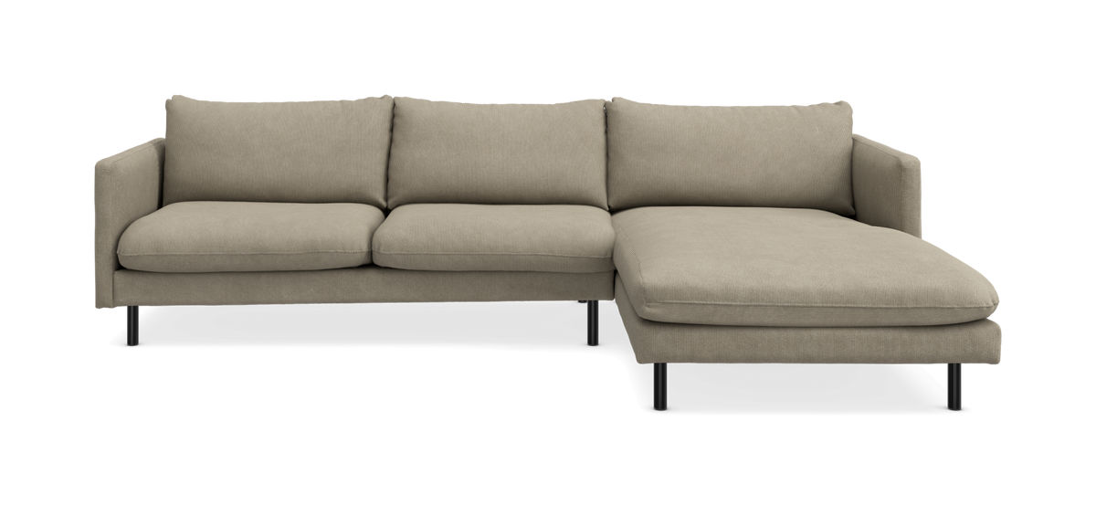 Beige hjørnesofa med chaiselong på højre side og slanke sorte ben.