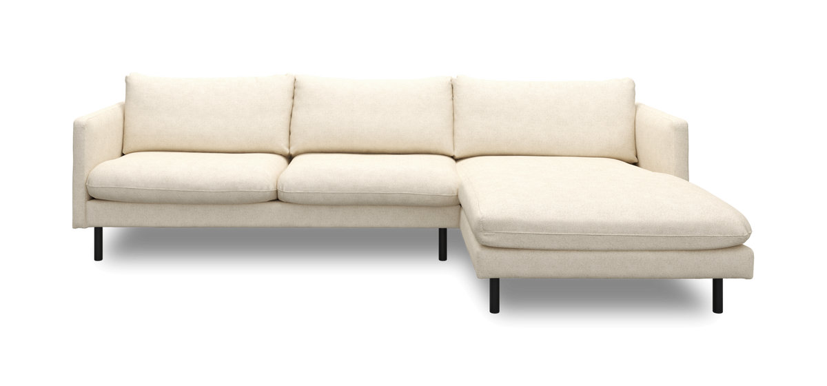 Beige hjørnesofa med højrevendt chaiselong og slanke sorte ben, frontvisning fritlagt.