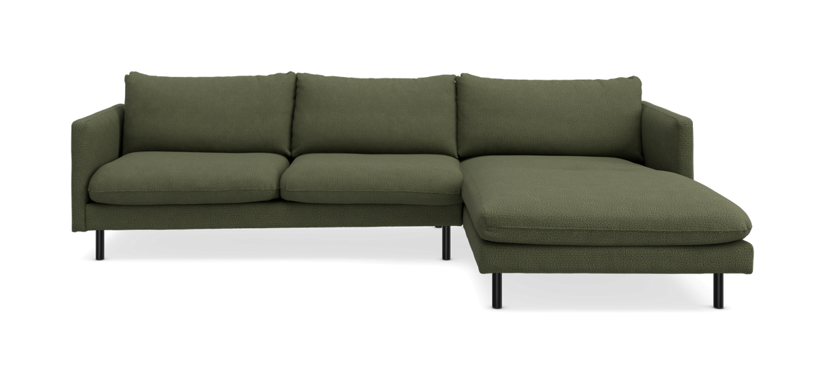 Grøn modulsofa med chaiselong til højre og slanke sorte ben, frilagt i studio.