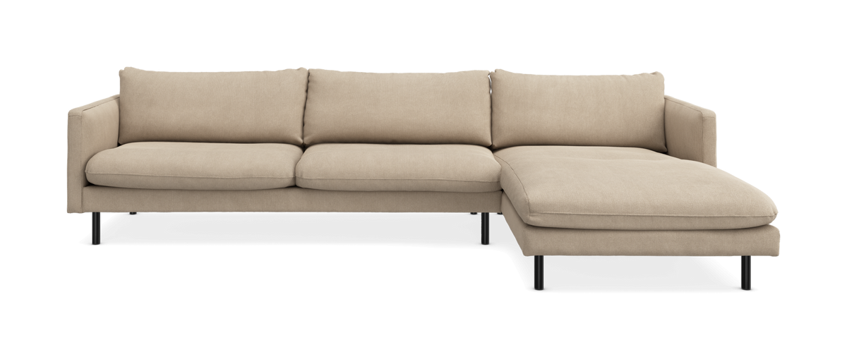 Beige hjørnesofa med chaiselong til højre på slanke sorte ben, set forfra som frilagt produkt.