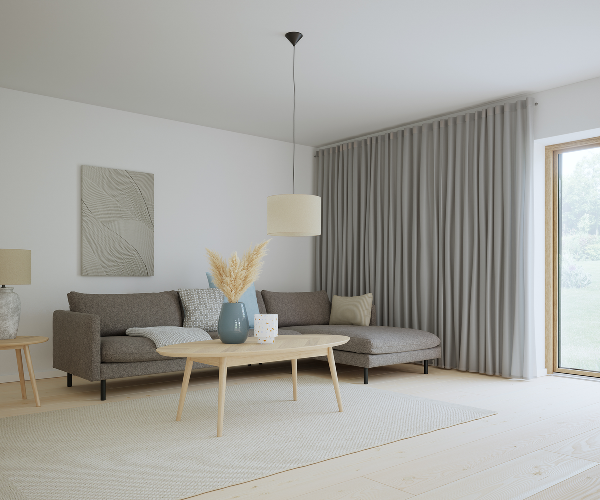 Lyst skandinavisk stue med grå hjørnesofa, lyse trægulve, beige tæppe, træ-sofabord og pendellampe; store grå gardiner og en blå vase med pampasgræs på bordet.