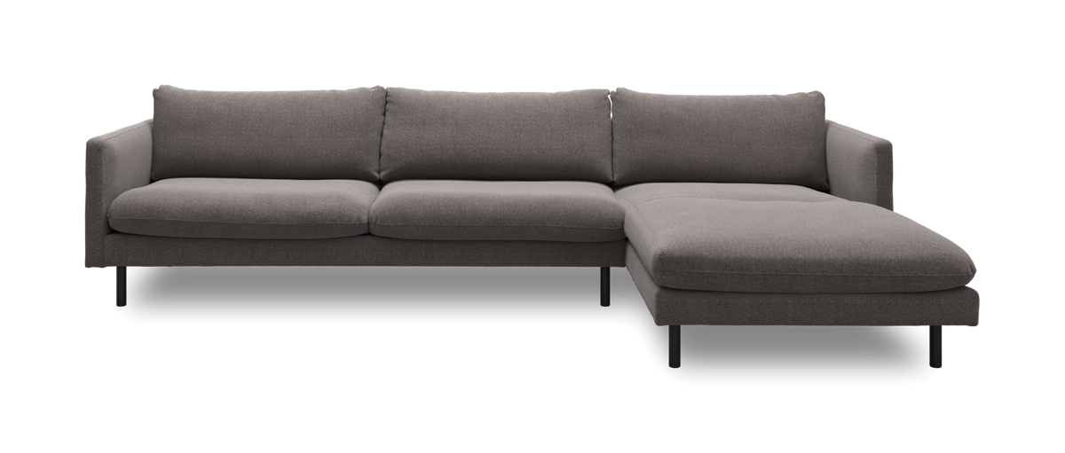 Grå højrevendt hjørnesofa med chaiselong og sorte metalben, frilagt i studie.