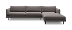 Grå højrevendt hjørnesofa med chaiselong og sorte metalben, frilagt i studie.