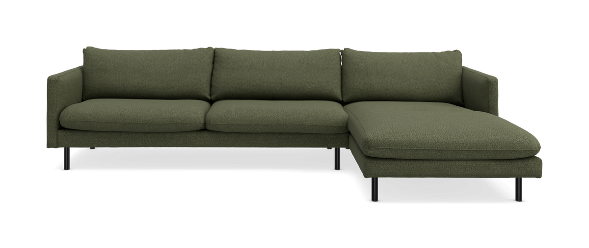 Grøn hjørnesofa med chaiselong til højre på sorte ben.