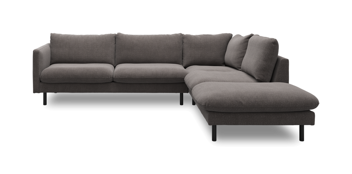 Grå L-formet hjørnesofa med chaiselong til højre og slanke sorte ben.