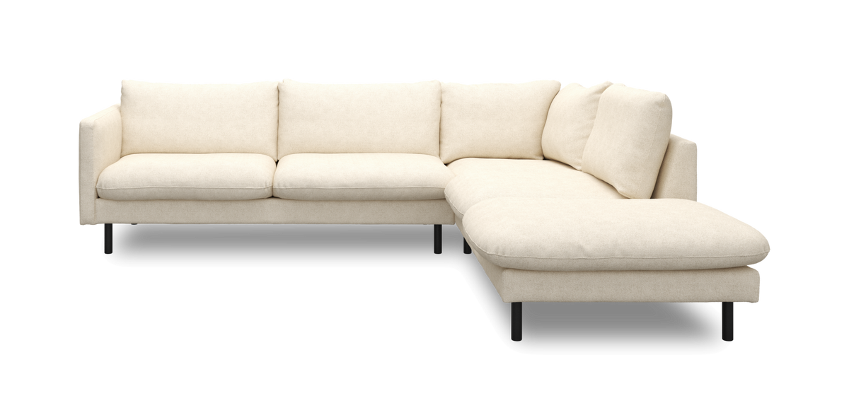 L-formet beige modulsofa med højrevendt chaiselong, bløde hynder og sorte ben, frilagt på hvid baggrund.