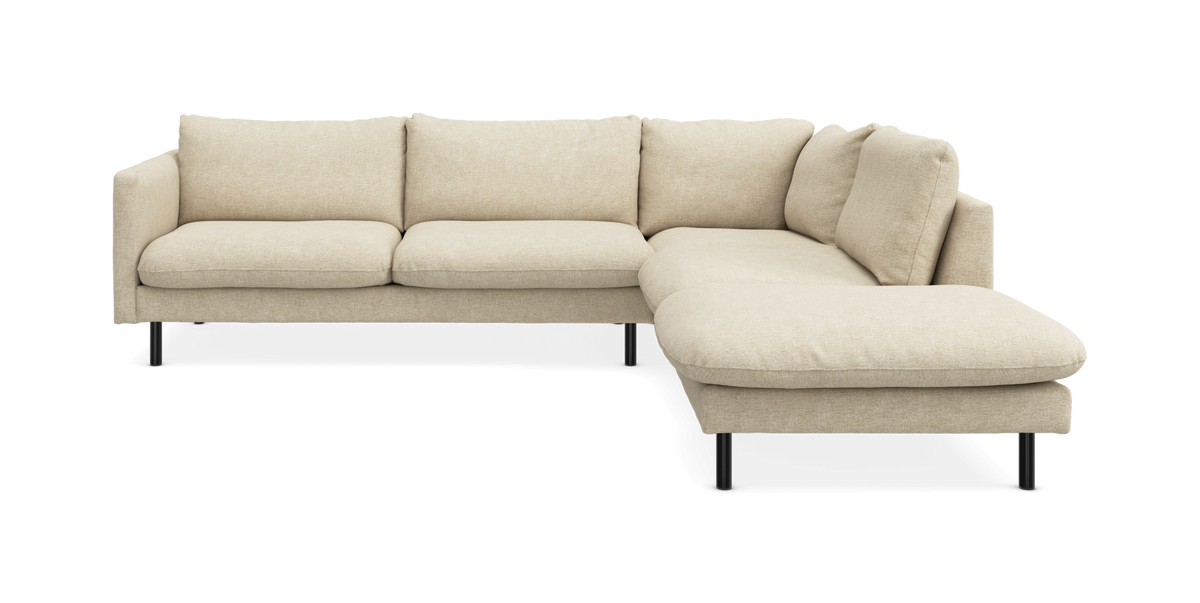 Beige L‑formet hjørnesofa med chaiselong til højre og slanke sorte ben, frilagt produktbillede.