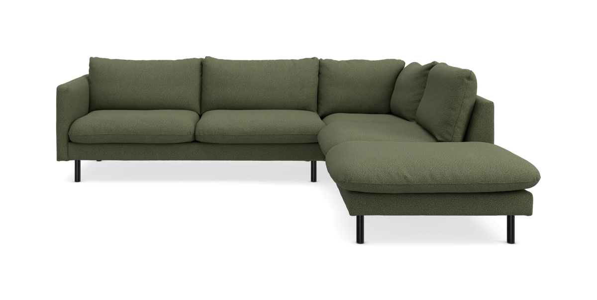 Grøn L-formet hjørnesofa med højre chaiselong, bouclé-lignende betræk og slanke sorte ben, frilagt studiobillede.