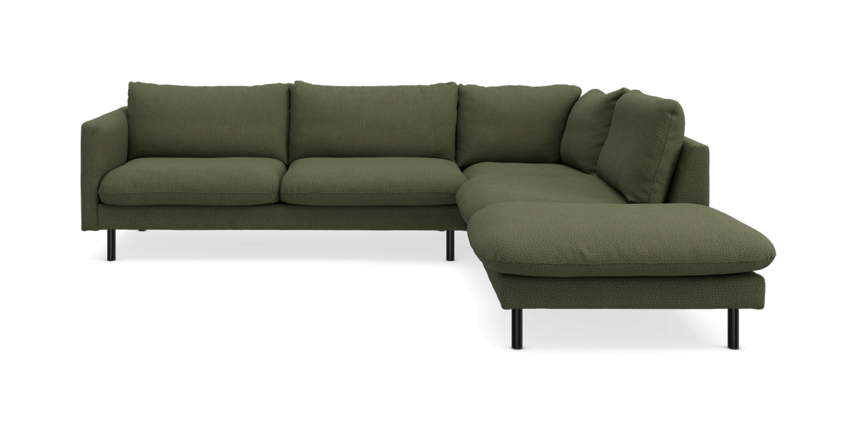 Grøn hjørnesofa med chaiselong til højre, moderne design på slanke sorte ben.