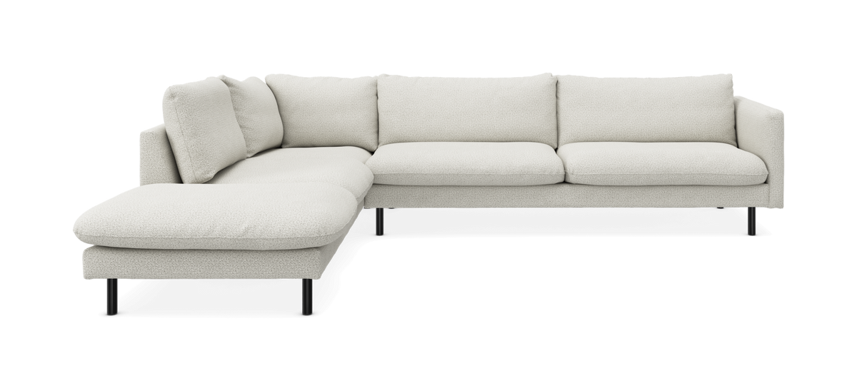 L-formet lysebeige/hvid stofsofa med venstrevendt chaiselong og sorte ben, fritlagt på hvid baggrund.