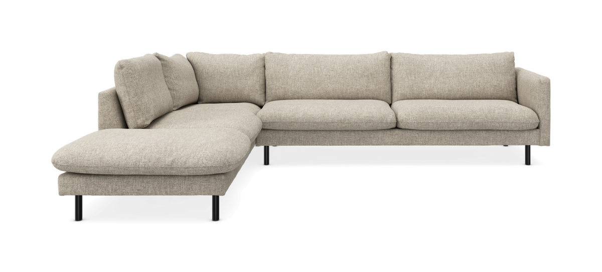 Beige L‑formet hjørnesofa med chaiselong og slanke sorte ben i moderne, minimalistisk design.