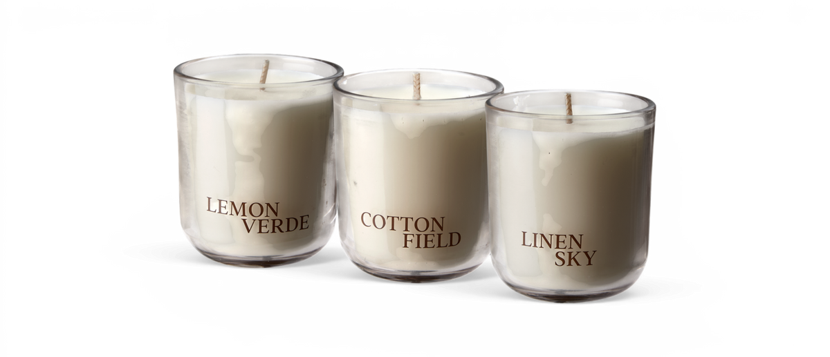 Tre hvide duftlys i glas med etiketterne LEMON VERDE, COTTON FIELD og LINEN SKY.