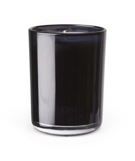 Mørkt duftlys i glas, LINEN SKY, på hvid baggrund.