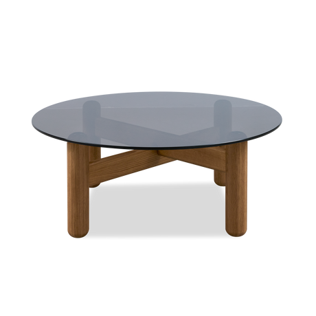 Lys stue med grå modulsofa, runde træborde, neutral farvepalette og grønne planter i dagslys.