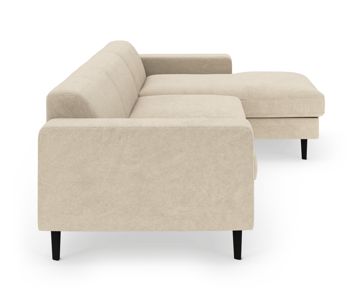 Beige hjørnesofa med chaiselong til højre og slanke sorte ben, fritlagt på ren studiebaggrund.