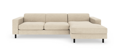 Beige modulsofa med chaiselong til højre, rene linjer og sorte ben, fritlagt på hvid baggrund.