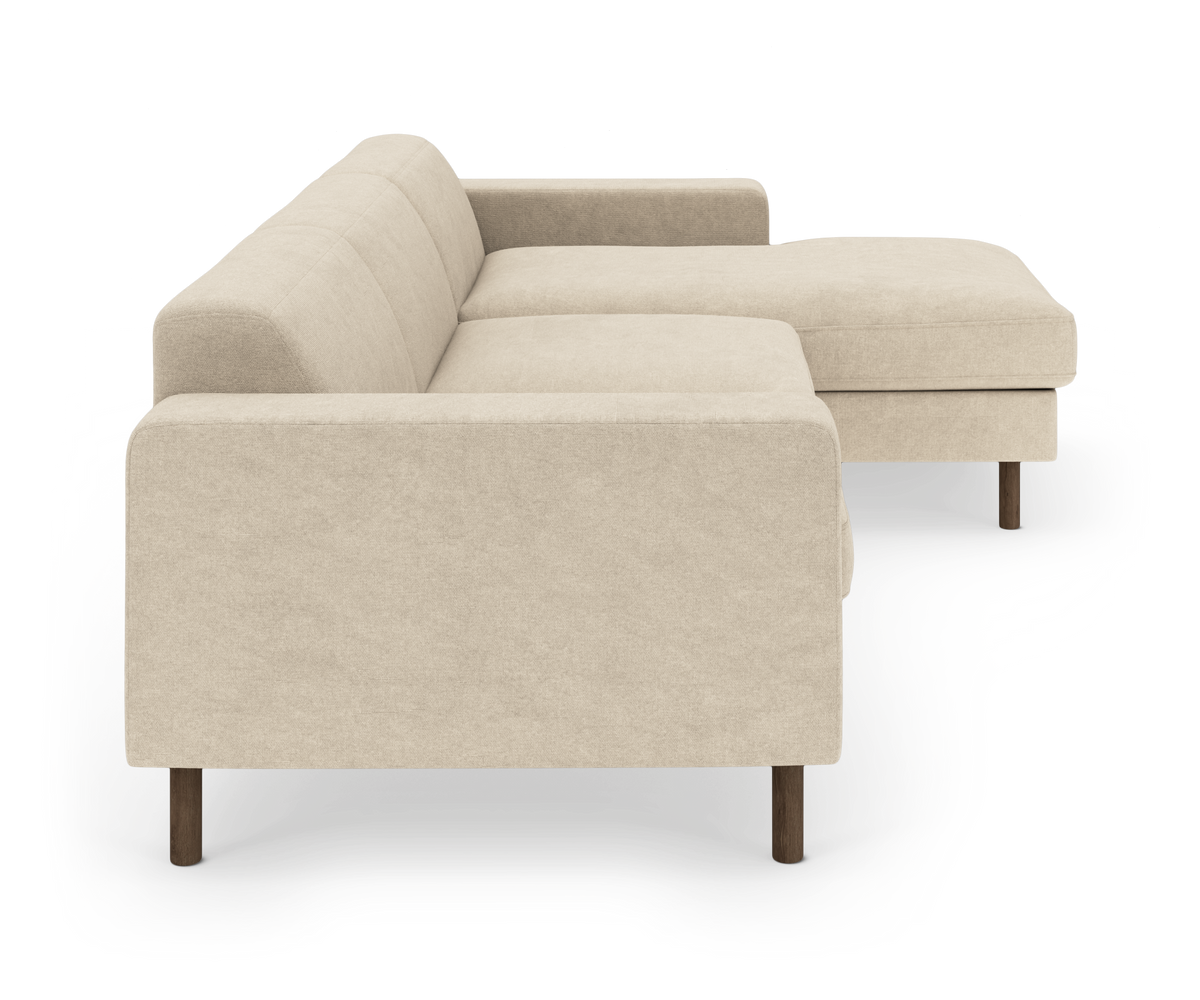 Beige hjørnesofa med chaiselong til højre og træben, frilagt på hvid baggrund.