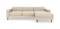 Beige modulsofa med chaiselong til højre og runde træben, frilagt på hvid baggrund.
