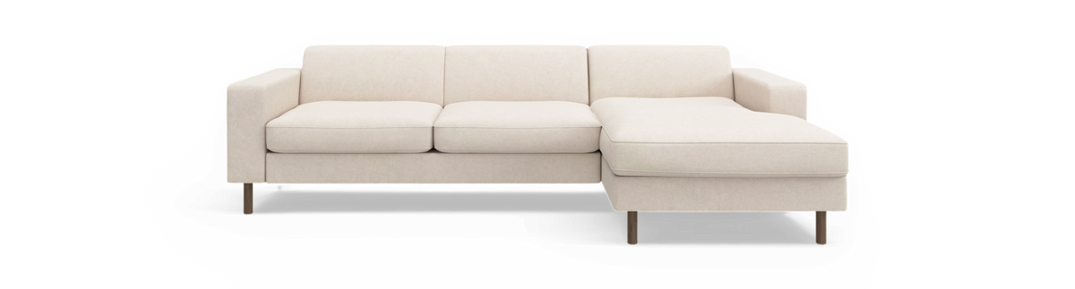 Beige hjørnesofa med chaiselong til højre, tre rygpuder og træben, frilagt mod sort baggrund.