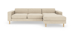 Beige hjørnesofa med chaiselong til højre, træben og moderne minimalistisk design, fritstående på hvid baggrund.
