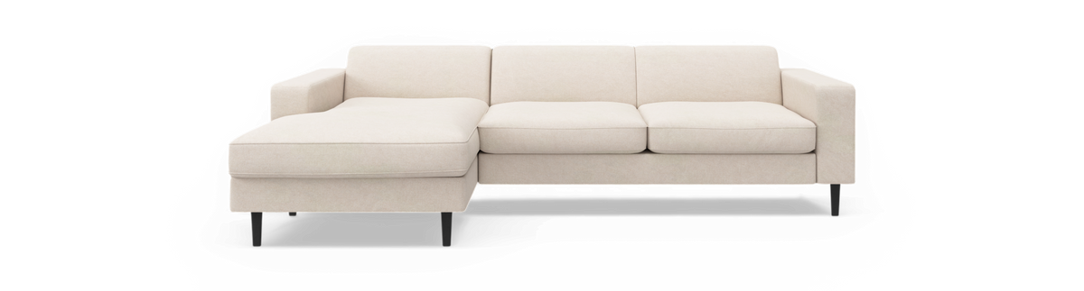 Beige tresæders modulsofa med venstrevendt chaiselong og sorte ben, frilagt på sort baggrund.