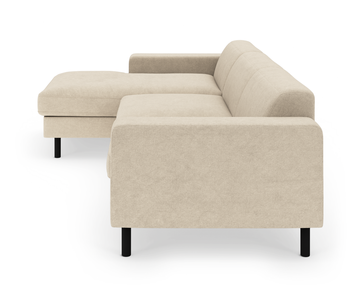 Beige hjørnesofa med chaiselong til venstre, glatte puder og sorte ben, frilagt på hvid baggrund.