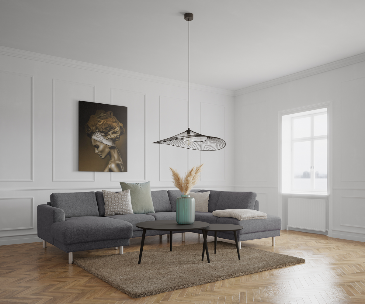 Lyst stue med grå hjørnesofa, sorte runde sofaborde og netpendel over, vase med pampasgræs på bordet og stort vindue til højre; vægpaneler og kunst på væggen.