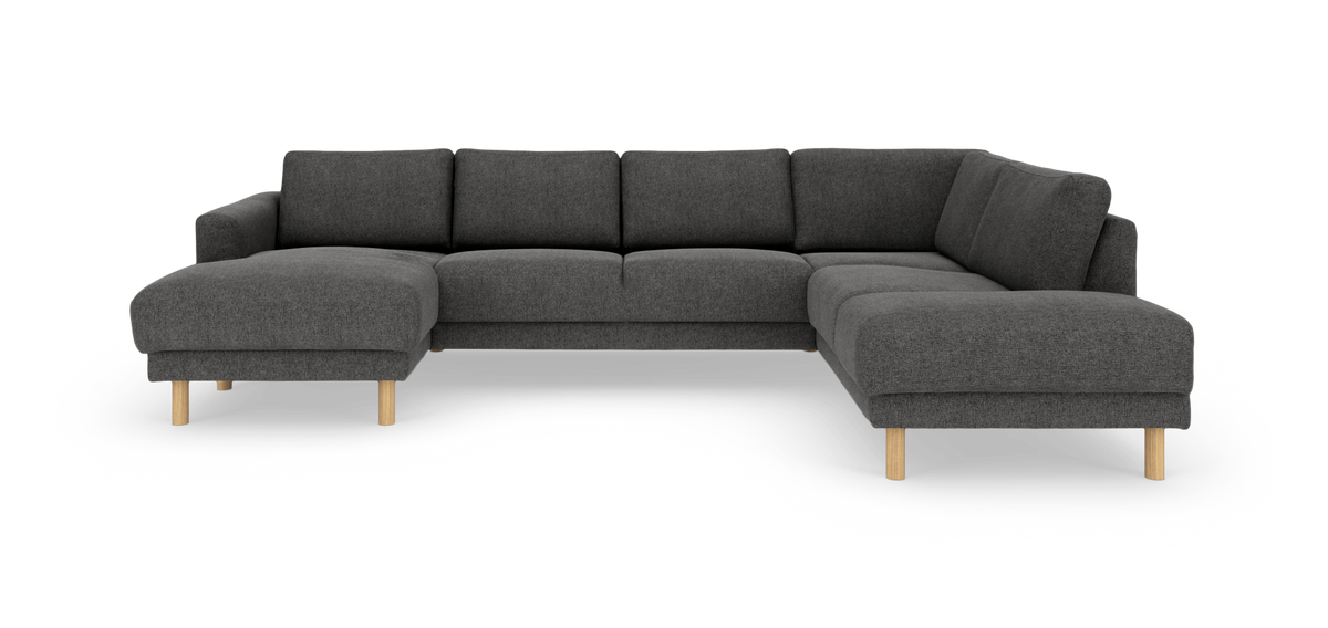 Mørkegrå modulsofa i U‑form med chaiselong i begge ender og lyse træben, frilagt på hvid baggrund.