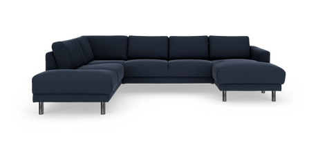 Mørkeblå hjørnesofa i stof med kromben, frilagt på hvid baggrund.