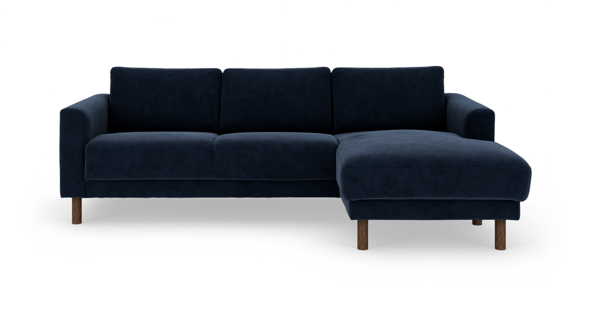 Mørkeblå hjørnesofa med chaiselong til højre og træben, frilagt på hvid baggrund.
