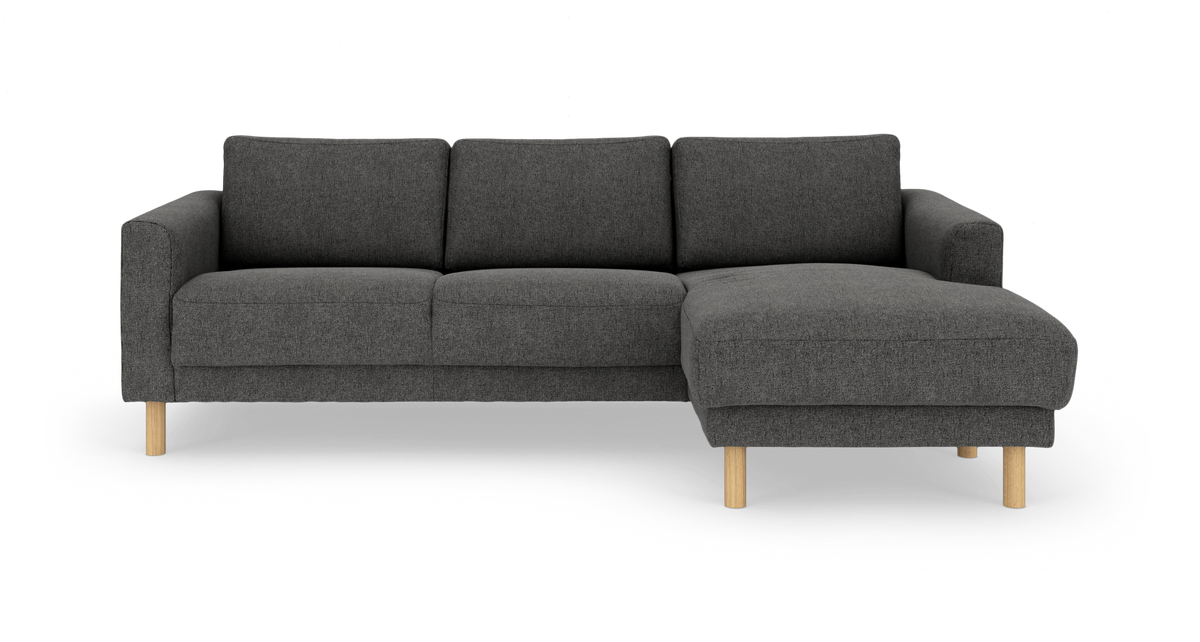 Mørkegrå 3-personers sofa med højrevendt chaiselong og lyse træben, frilagt på hvid baggrund.