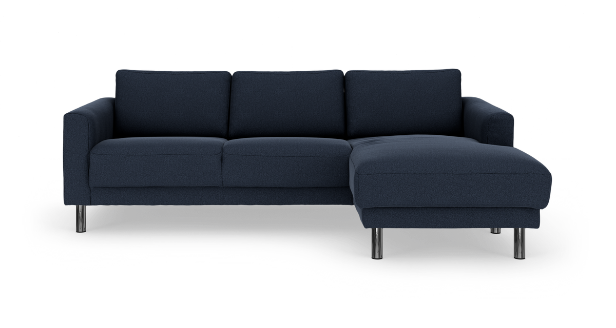 Mørkeblå hjørnesofa med chaiselong til højre på kromben, frilagt på hvid baggrund.