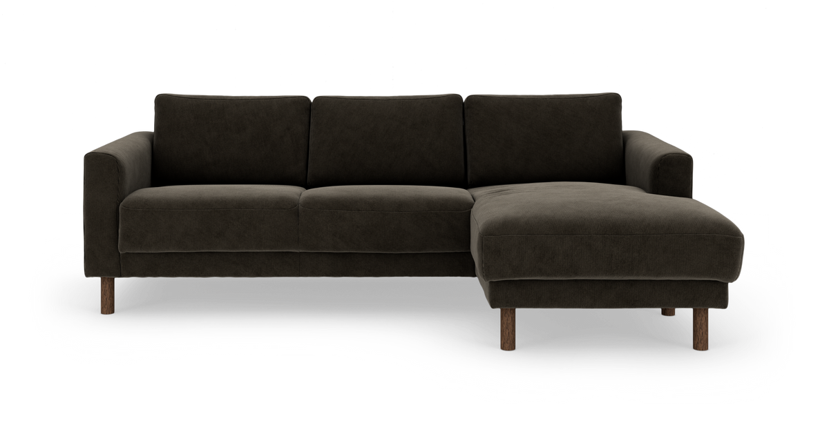 Mørkegrå hjørnesofa med chaiselong til højre og runde træben, frilagt på hvid baggrund.