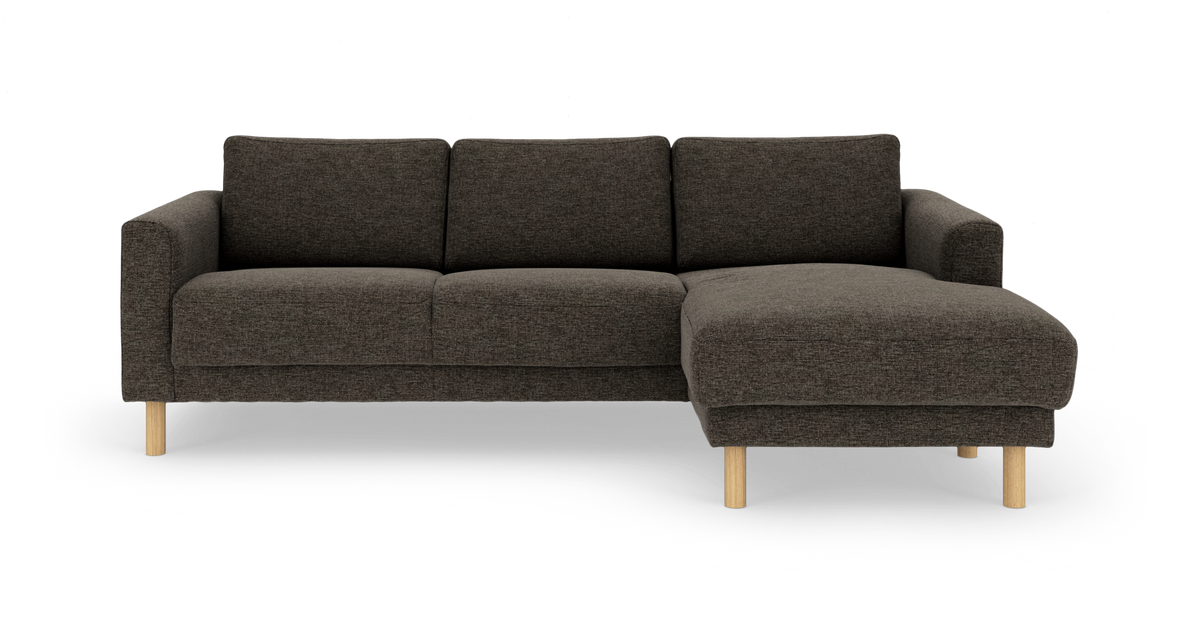 Mørkegrå hjørnesofa med chaiselong til højre, stofbetræk og lyse træben, frilagt på hvid baggrund.