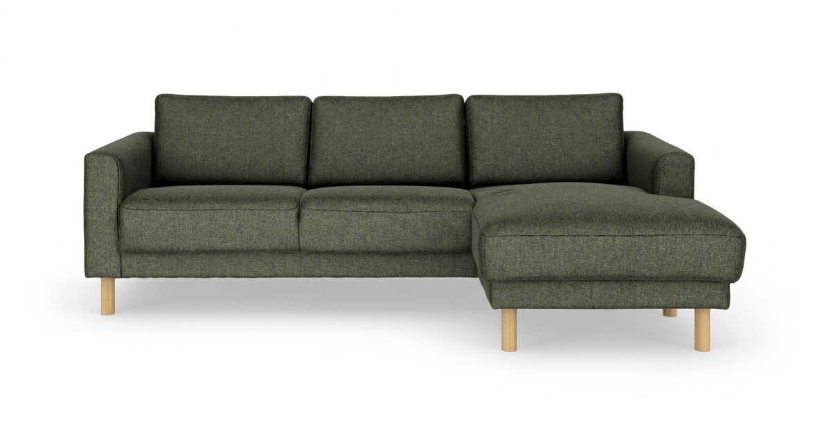 Mørkegrøn hjørnesofa med chaiselong til højre, stofbetrukket med træben, frontvisning på hvid studiobaggrund.