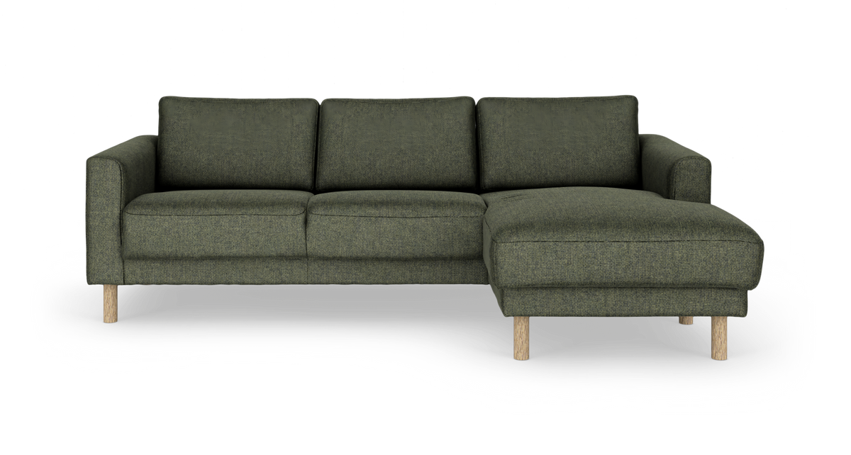 Grøn stofsofa med chaiselong til højre og runde træben, set forfra mod hvid baggrund.
