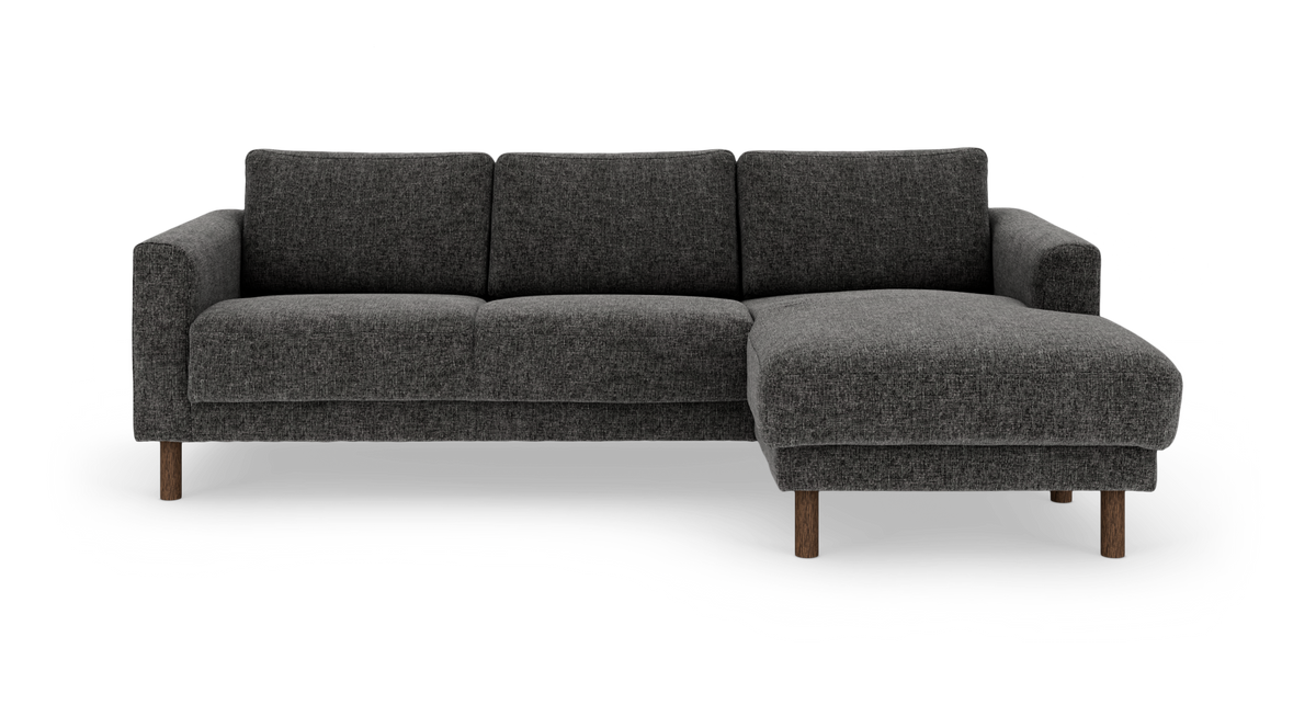 Mørkegrå hjørnesofa med chaiselong til højre og ben i mørkt træ, set forfra.