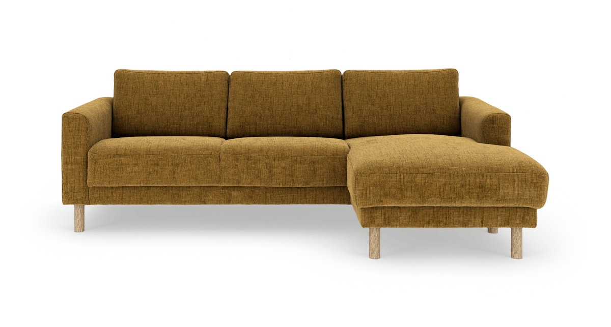 Sennepsgul sofa med chaiselong til højre og runde træben, frilagt på hvid baggrund.