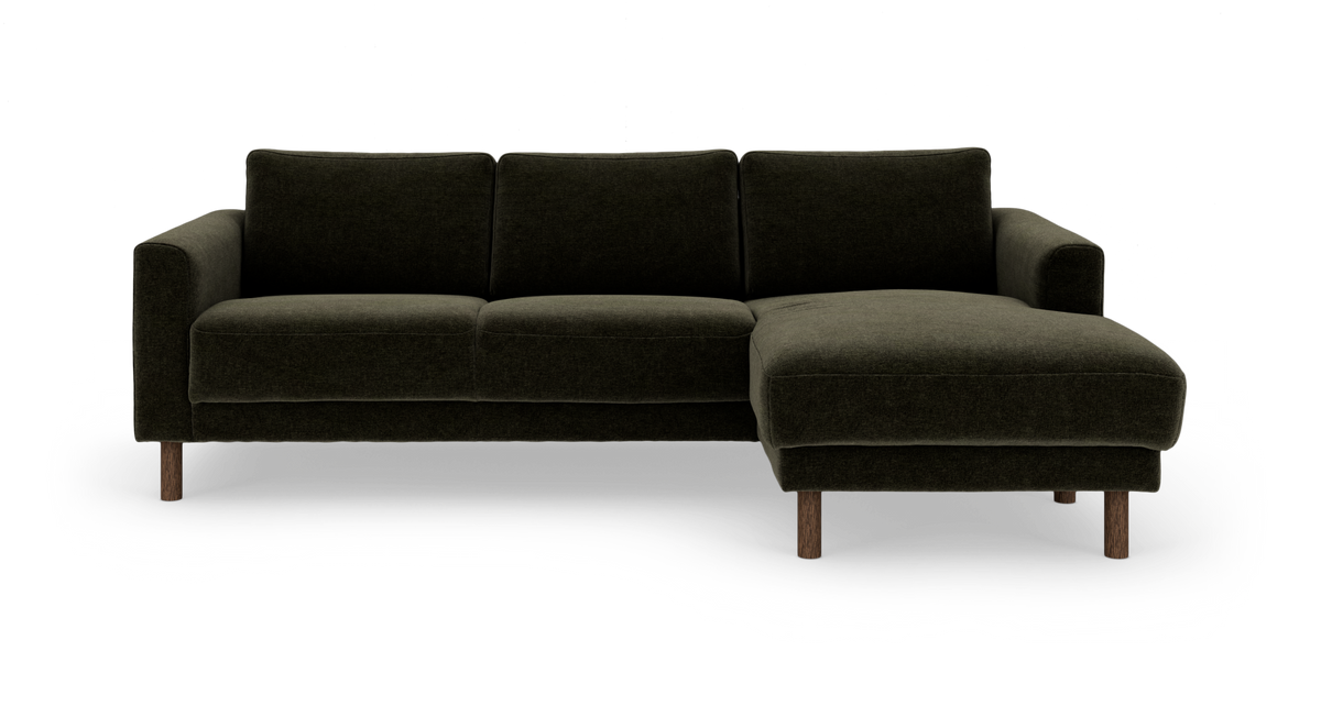 Mørkegrøn hjørnesofa med chaiselong til højre og runde træben, frilagt på hvid baggrund.